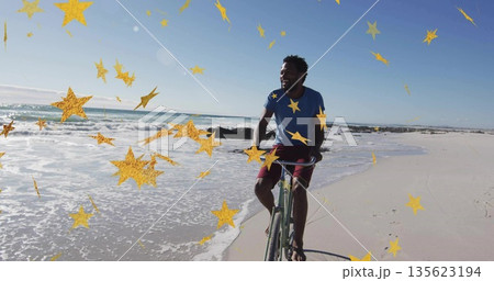 Bicycling man on bicycle along wet shoreline, golden star overlays drifting across sky, copy space Bicycling man on bicycle along wet shoreline, golden star overlays drifting across sky, copy space 135623194