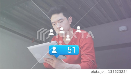 Man wearing red sweater viewing tablet on balcony, with user icons and 51 notification bubble 135623224