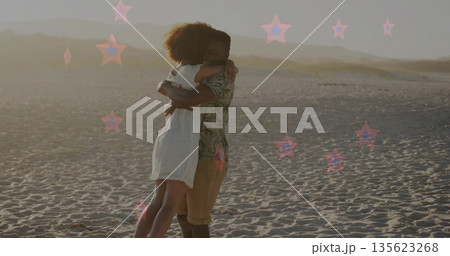Lifting and embracing couple wearing sundress and tropical shirt on sandy beach during golden hour 135623268