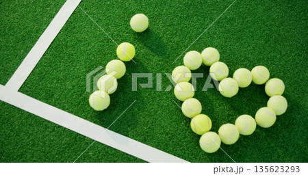 Displaying yellow tennis balls forming I heart shape on tennis court corner, with white court lines Displaying yellow tennis balls forming I heart shape on tennis court corner, with white court lines 135623293