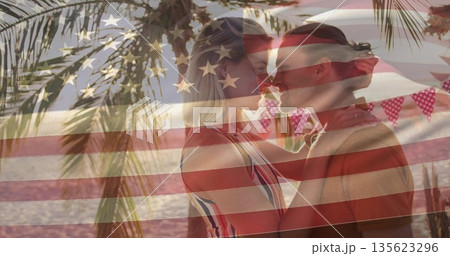 Touching foreheads couple on beach at sunset, with pennant flags and Stars-and-Stripes overlay Touching foreheads couple on beach at sunset, with pennant flags and Stars-and-Stripes overlay 135623296