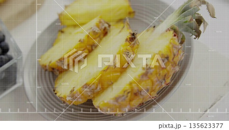 Displaying fresh pineapple slices on grey plate on wooden table, with blueberries in container Displaying fresh pineapple slices on grey plate on wooden table, with blueberries in container 135623377