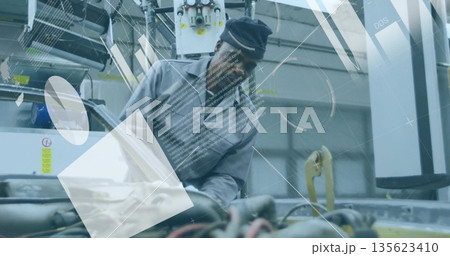 Leaning mechanic in coveralls and cap inspecting engine hoses in repair bay with diagnostic overlay Leaning mechanic in coveralls and cap inspecting engine hoses in repair bay with diagnostic overlay 135623410