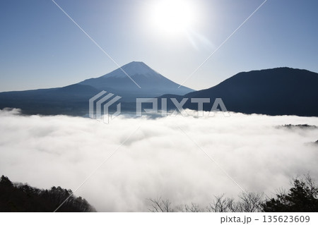 雲海に隠れる本栖湖と対岸にそびえる逆光の冠雪した富士山 雲海に隠れる本栖湖と対岸にそびえる逆光の冠雪した富士山 135623609