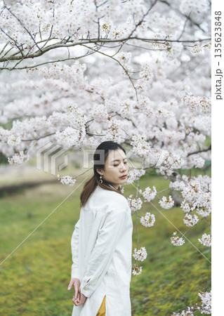 満開の桜を背景にして、笑顔の若い女性 満開の桜を背景にして、笑顔の若い女性 135623848