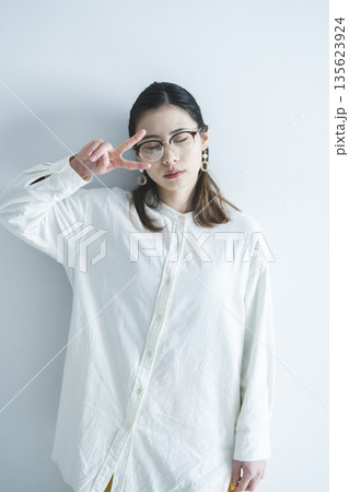 ピースサインをするメガネをかけた女性 135623924