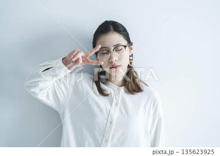 ピースサインをするメガネをかけた女性 135623925