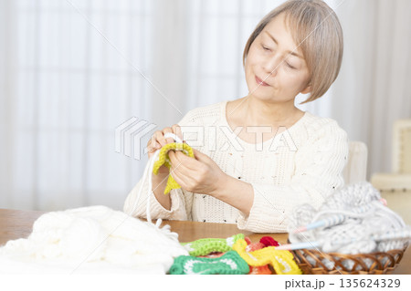 リビングで毛糸のアクリルたわしを編むシニア女性 135624329