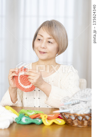 リビングで毛糸のアクリルたわしを編むシニア女性 リビングで毛糸のアクリルたわしを編むシニア女性 135624340