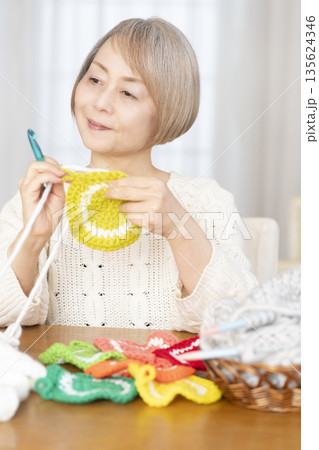 リビングで毛糸のアクリルたわしを編むシニア女性 リビングで毛糸のアクリルたわしを編むシニア女性 135624346