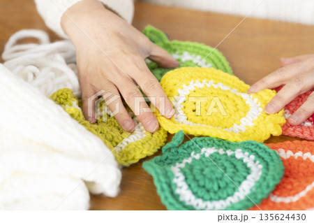リビングで毛糸のアクリルたわしを編むシニア女性の手元アウトフォーカス 135624430