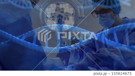 Surgical team in blue gowns performing surgery in operating room, with light and DNA helix graphic Surgical team in blue gowns performing surgery in operating room, with light and DNA helix graphic 135624673