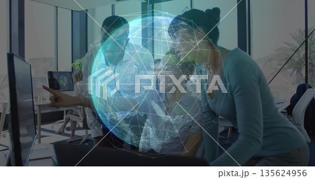 Team wearing formal attire collaborating around monitor in office, with digital globe overlay Team wearing formal attire collaborating around monitor in office, with digital globe overlay 135624956