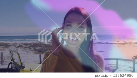 Standing woman wearing mustard top at wooden fence on beach walkway, yellow vehicle, dunes, ocean 135624980