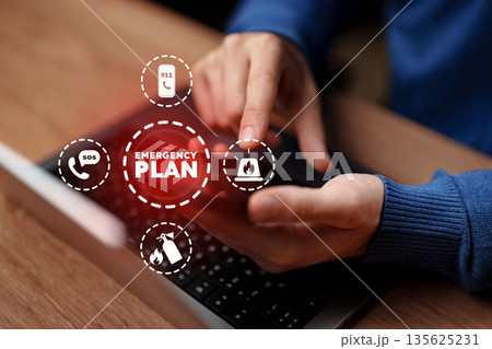 Creating an emergency plan with a phone and laptop in a home office setting Creating an emergency plan with a phone and laptop in a home office setting 135625231