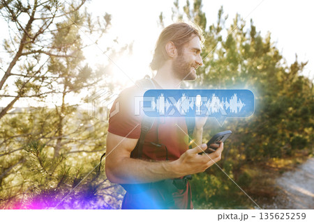 Man walks on trail while using smartphone for voice recording in a forest area Man walks on trail while using smartphone for voice recording in a forest area 135625259
