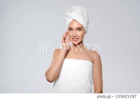 Woman poses after shower in white towel with light background in a simple setting 135625297