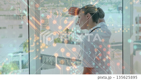 Shielding doctor wearing lab coat, gazing via hospital window over circuit overlay, copy space 135625895
