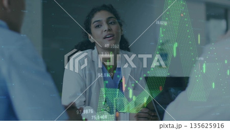 Leading doctor in lab coat briefing medical team at conference table projecting financial charts 135625916