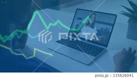Hosting remote team reviewing checklist on laptop at home desk with line graphs and desk plant 135626041