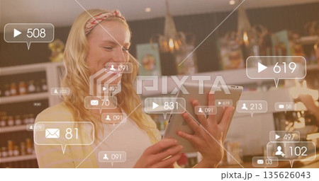 Woman holding tablet tapping screen in retail shop, with shelving and digital overlays, copy space 135626043