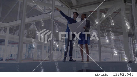 Two professionals wearing formal attire holding blueprint and pointing in unfinished building Two professionals wearing formal attire holding blueprint and pointing in unfinished building 135626049
