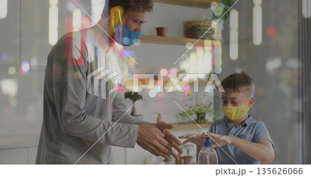 Guiding father and son wearing face masks practicing hand sanitizing on counter, with pump bottle 135626066