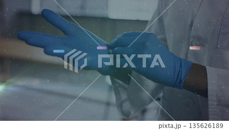 Applying blue nitrile gloves doctor wearing white lab coat in clinical lab, with blurred cabinets Applying blue nitrile gloves doctor wearing white lab coat in clinical lab, with blurred cabinets 135626189
