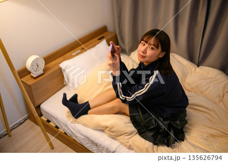 ベッドでスマホを操作する女子高生 135626794