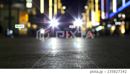 Shining vehicle headlights moving along dark street at night, with floating chat icon and play icon Shining vehicle headlights moving along dark street at night, with floating chat icon and play icon 135627142