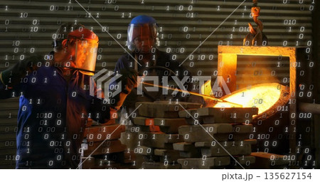Foundry workers pouring molten metal from crucible in foundry workshop, wearing protective gear 135627154