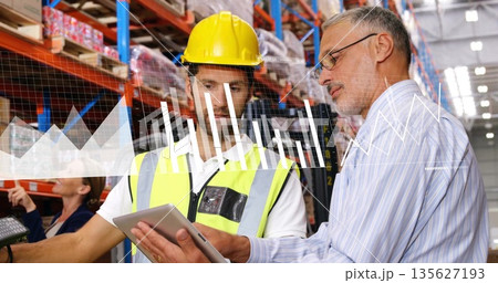 Reviewing stock two colleagues wearing vest examining tablet at warehouse, with scanner and charts Reviewing stock two colleagues wearing vest examining tablet at warehouse, with scanner and charts 135627193
