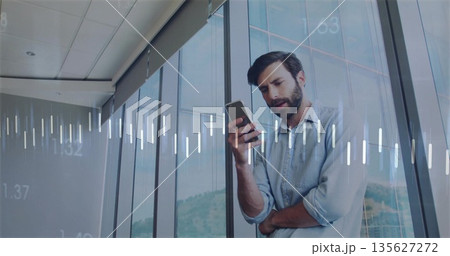Checking man wearing blue shirt beside glass windows in office, with smartphone and data overlays Checking man wearing blue shirt beside glass windows in office, with smartphone and data overlays 135627272