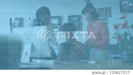 Collaborating colleagues analyzing data on tablet at modern office desk, with desktop monitor 135627317