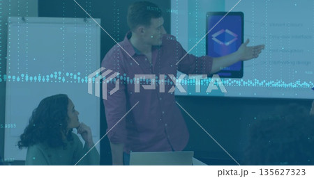 Presenting man in formal shirt gesturing toward screen in conference room with laptop and flipchart Presenting man in formal shirt gesturing toward screen in conference room with laptop and flipchart 135627323