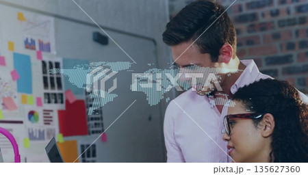 Two coworkers reviewing data on laptop displaying digital map in office workspace, copy space 135627360