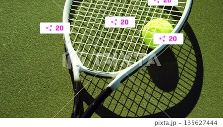 Resting tennis racket and ball with digital overlay share icons floating over green tennis court Resting tennis racket and ball with digital overlay share icons floating over green tennis court 135627444