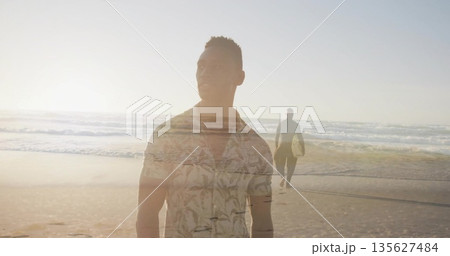 Standing man wearing palm shirt gazing at sea at sunset, surfer carrying surfboard walking shore Standing man wearing palm shirt gazing at sea at sunset, surfer carrying surfboard walking shore 135627484