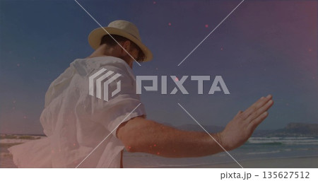 Pointing man in straw fedora hat, white linen shirt extending arm toward sea shore, copy space 135627512