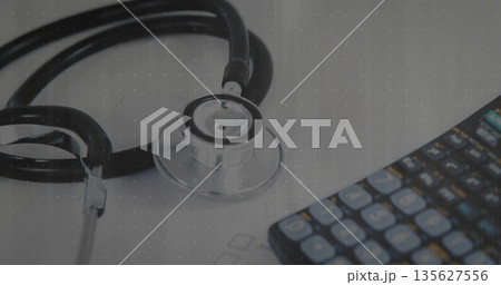 Arranging medical stethoscope and calculator on clinic desk surface, with printed sheet 135627556