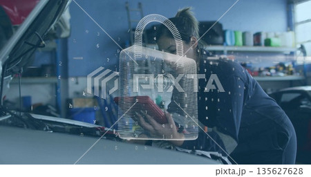 Inspecting woman mechanic wiping engine bay with red cloth in garage bay, digital padlock overlay Inspecting woman mechanic wiping engine bay with red cloth in garage bay, digital padlock overlay 135627628