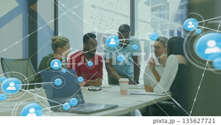 Collaborating professionals reviewing papers and laptops in meeting room, with network overlays Collaborating professionals reviewing papers and laptops in meeting room, with network overlays 135627721