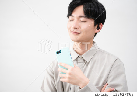 有線イヤホンで音楽を聴く若い男性 135627865