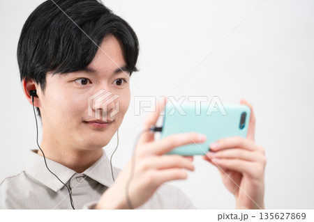 有線イヤホンで音楽を聴く若い男性 135627869