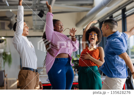 Celebrating success, diverse colleagues expressing joy and excitement in modern office 135628276