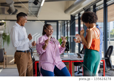 Celebrating success, African American colleagues smiling and clapping in modern office 135628278