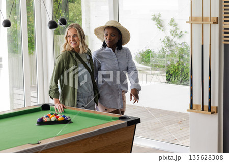 Two women enjoying leisure time by pool table in bright, modern room 135628308