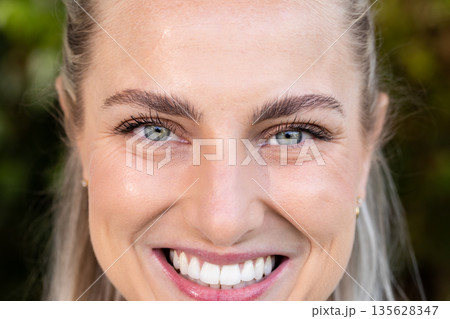 Smiling brightly outdoors, woman showing happiness in sunny park setting 135628347