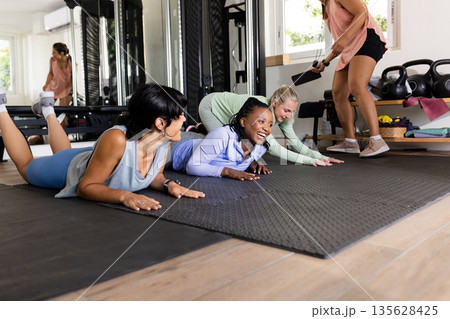Women exercising on gym mats, laughing and enjoying group fitness session together Women exercising on gym mats, laughing and enjoying group fitness session together 135628425