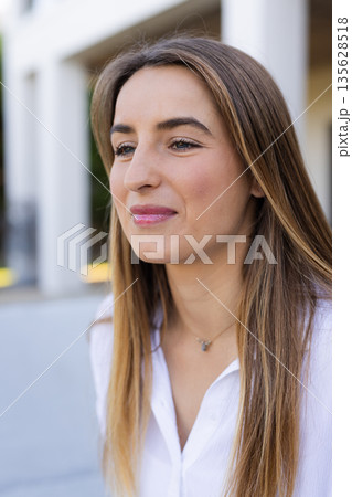 Smiling woman outdoors enjoying sunny day, wearing white shirt, looking content Smiling woman outdoors enjoying sunny day, wearing white shirt, looking content 135628518